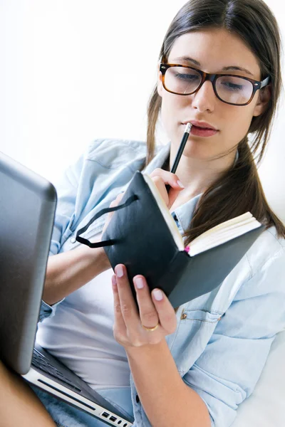 Young woman taking notes at home — Stock Photo, Image