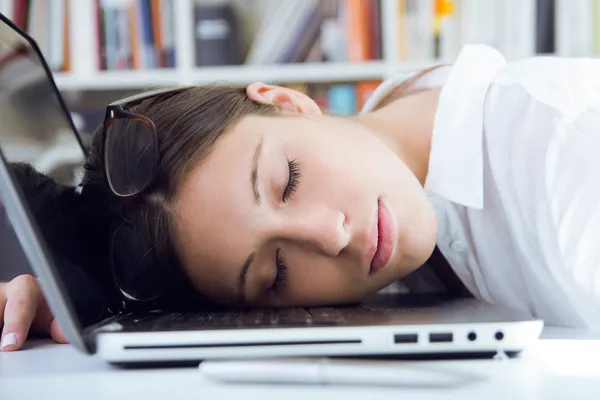 Femme dormant sur son ordinateur portable dans le lieu de travail — Photo