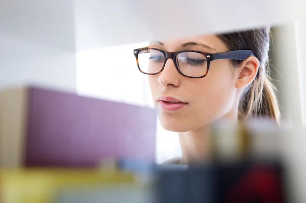 Ung student söker en bok i biblioteket — Stockfoto