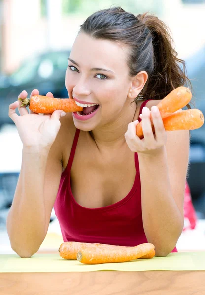 Hezká žena doma jíst mrkev — Stock fotografie
