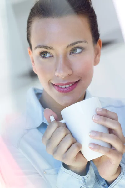 Молода жінка має каву на кухні — стокове фото