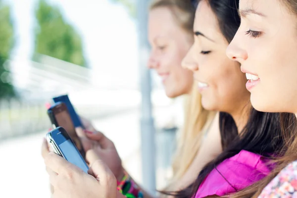 Three girls chatting with their smartphones — Stock Photo, Image