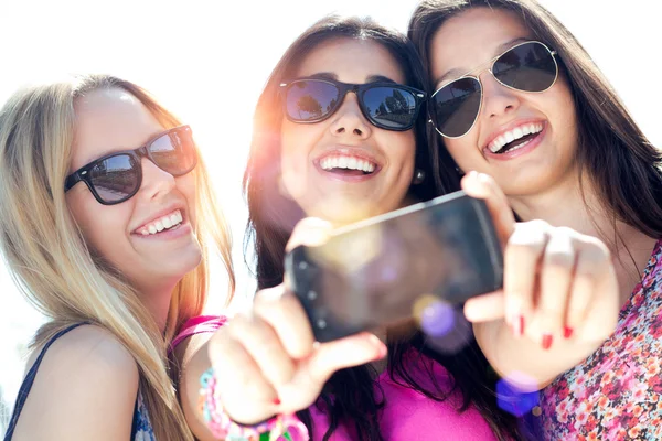 Tre vänner ta foton med en smartphone Royaltyfria Stockfoton
