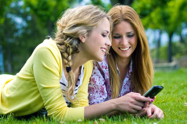 Two sisters with smartphone at the park — Stock Photo, Image
