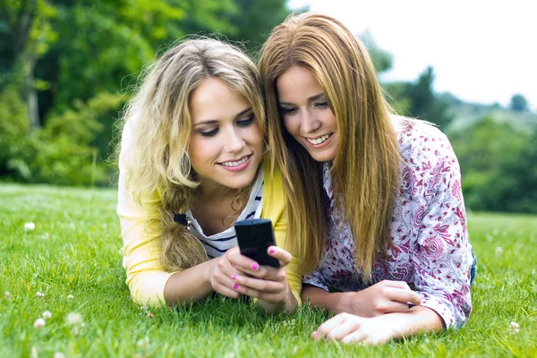 Twee zusters met smartphone in het park — Stockfoto