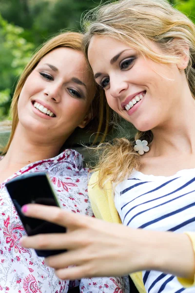 Two sisters with smartphone at the park — Stock Photo, Image