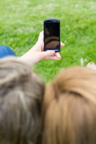 공원에서 스마트폰으로 두 자매 — 스톡 사진
