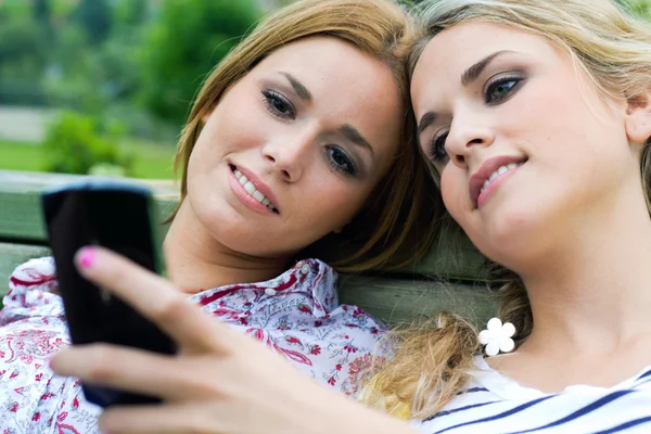 Two sisters with smartphone at the park — Stock Photo, Image