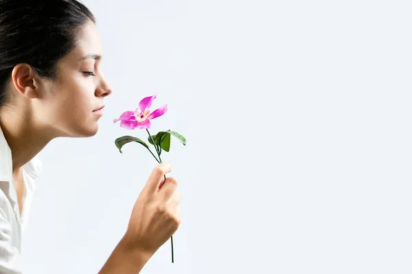 Foto de perfil de uma menina bonita cheirando uma flor — Fotografia de Stock