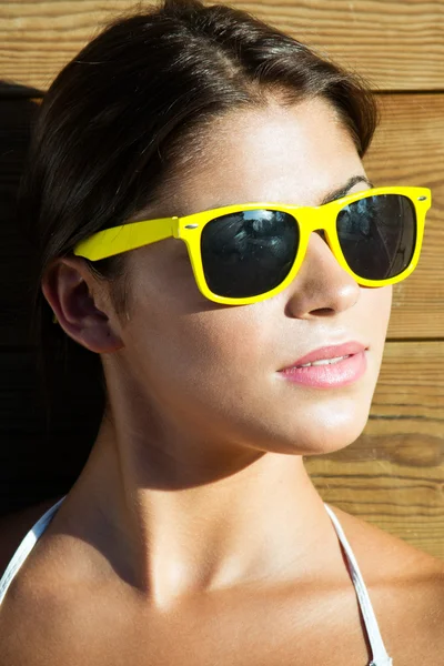Portrait of a beautiful woman in a park with yellow sunglasses — Stock Photo, Image
