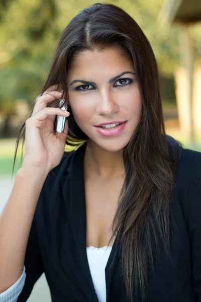 Hermosa mujer de negocios morena hablando por teléfono inteligente en el pa — Foto de Stock