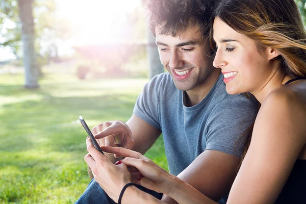 在公园的智能手机与快乐年轻夫妇 — 图库照片