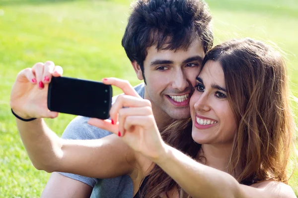 Feliz jovem casal com smartphone no parque — Fotografia de Stock