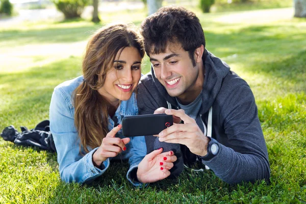 Feliz jovem casal com smartphone no parque — Fotografia de Stock