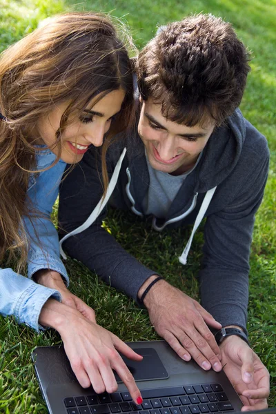 Porträt eines jungen Paares im Park mit einem Laptop — Stockfoto