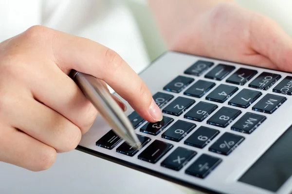 Manos de mujer con una calculadora y pluma —  Fotos de Stock