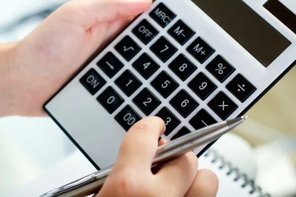 Manos de mujer con una calculadora y pluma —  Fotos de Stock