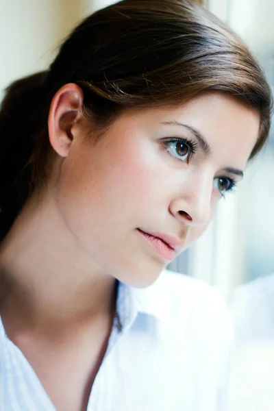 Young woman thinking and looking out the window — Stock Photo, Image