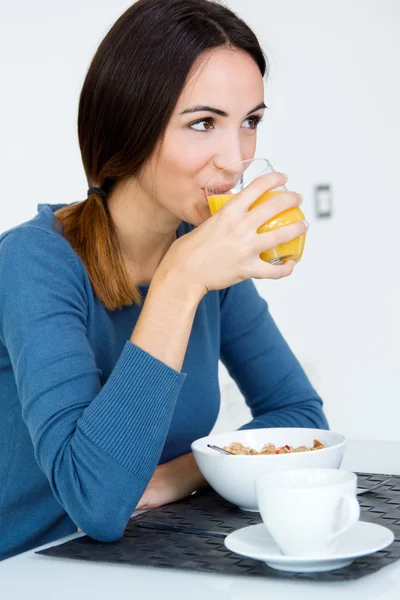 Ung kvinna njuter av orange juicet i köket — Stockfoto