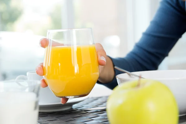 Woman's hand grabbing a glass of orange juice at breakfast — Stock Photo, Image