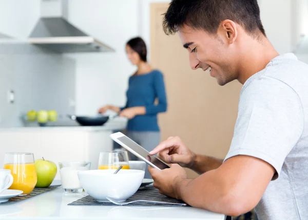 Pareja en la cocina preparando el desayuno y navegar por Internet — Foto de Stock