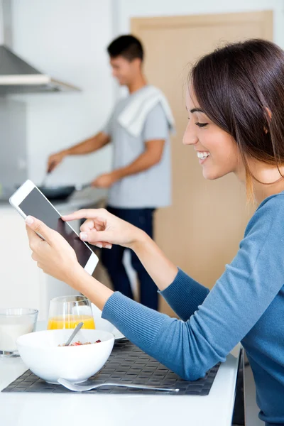 Paar in de keuken voorbereiding ontbijt en surfen op internet — Stockfoto