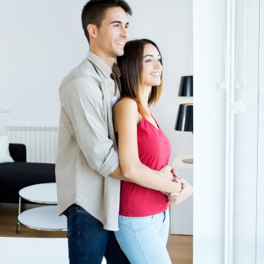 mutlu genç bir çift yeni zemin pencereden dışarı bakarak