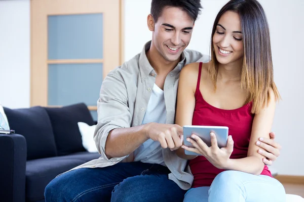 Pareja joven feliz en casa usando una tableta digital — Foto de Stock