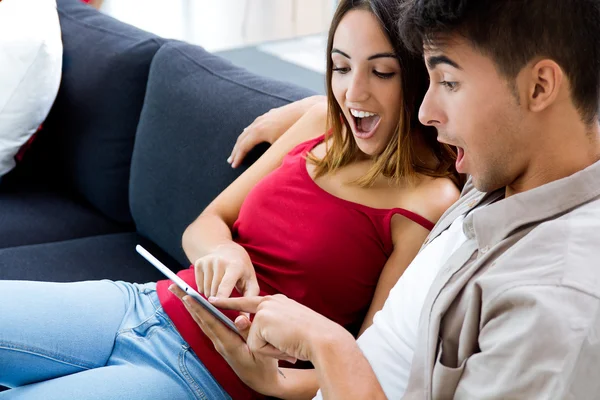 Pareja joven feliz en casa usando una tableta digital — Foto de Stock