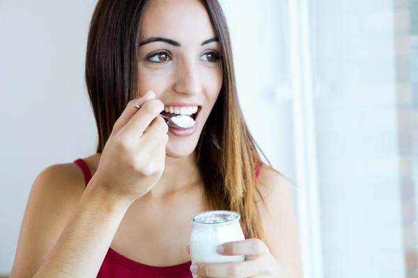 Mujer joven en casa comiendo yogur — Foto de Stock