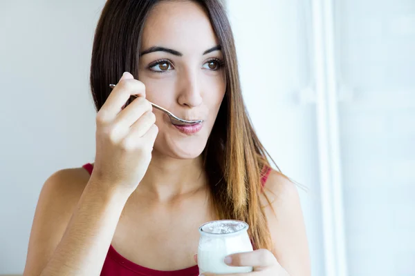 Mujer joven en casa comiendo yogur —  Fotos de Stock