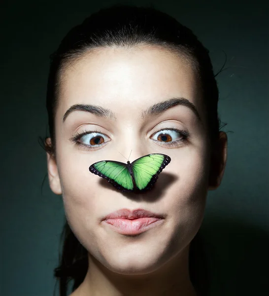 Verrast meisje met een vlinder op haar neus — Stockfoto
