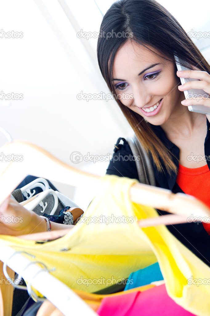 young woman talking on the phone while shopping for clothes