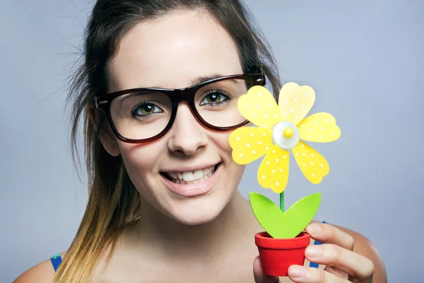 Hermosa joven que muestra una margarita artificial — Foto de Stock