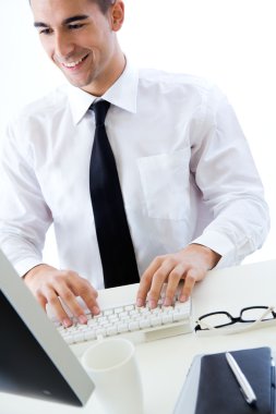 Modern ofiste bilgisayarla çalışan mutlu genç bir iş adamı.