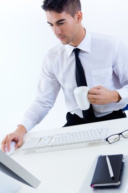 Genç iş adamı modern ofiste bilgisayarla çalışıyor.
