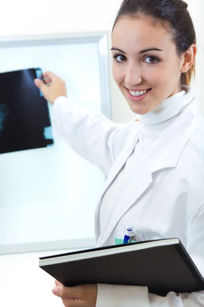 Attractive young female doctor examining x-ray results — Stock Photo, Image