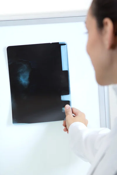 Attractive young female doctor examining x-ray results — Stock Photo, Image