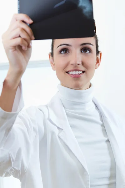 Attractive young female doctor examining x-ray results — Stock Photo, Image
