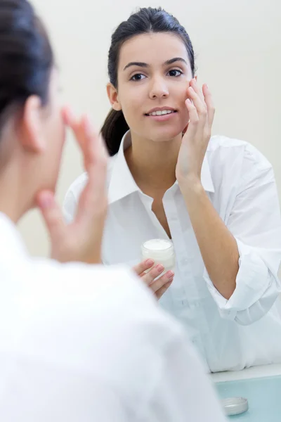 Cuidado corporal. Mujer aplicando crema en la cara —  Fotos de Stock