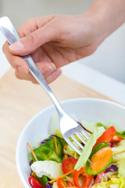 Jolie jeune femme mangeant de la salade à la maison — Photo