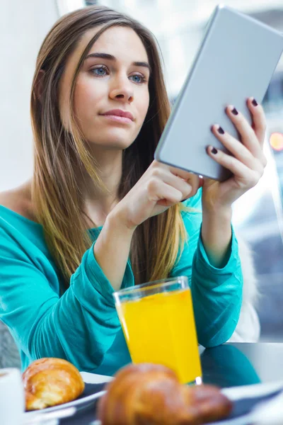 Mujer bonita usando la tableta mientras desayuna en la cafetería — Foto de Stock