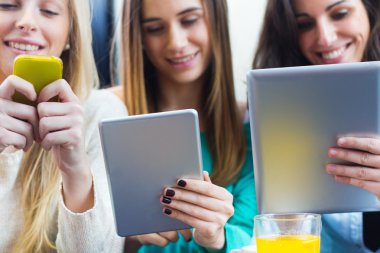 Friends surfing the net with smartphones and digital tablets clipart