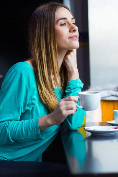 Wanita muda cantik duduk di kafe dengan secangkir kopi — Stok Foto