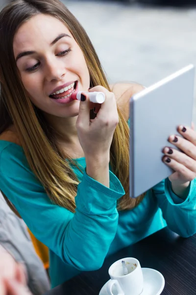 Mladá žena malovat rty s digitálním tabletu v kávy — Stock fotografie