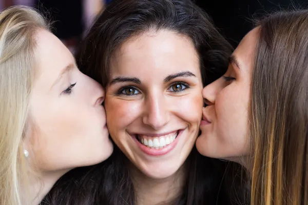 Linda chica sonriente besada en las mejillas por sus amigos . — Foto de Stock