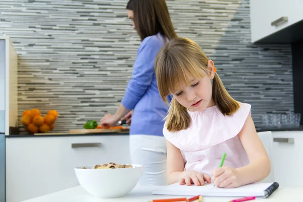 Kind tekenen met kleurpotloden, zittend aan tafel in de keuken thuis — Stockfoto