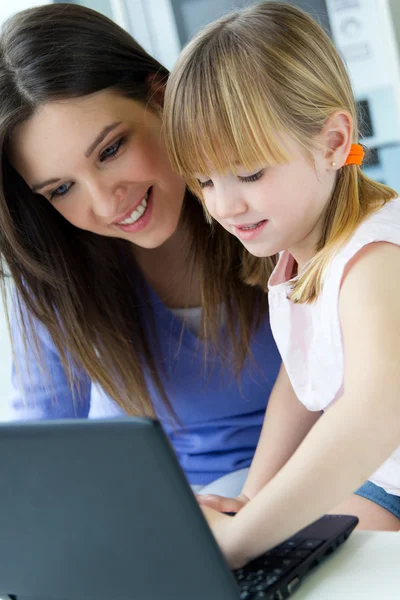 Mother and daughter using laptop in the kitchen — Stock Photo, Image