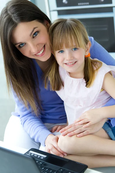 Mother and daughter using laptop in the kitchen — Stock Photo, Image