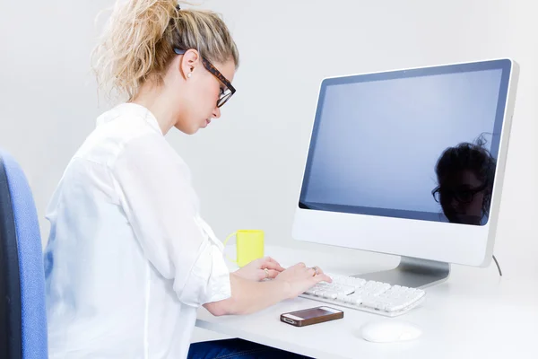 Молодая женщина работает из дома за компьютером — стоковое фото